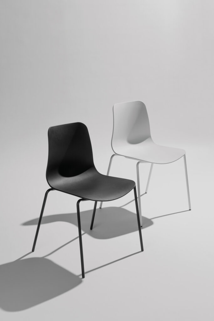 Curvo stoelen in wit en zwart samen opgesteld in een stijlvolle fotostudio met neutrale achtergrond en zachte belichting, waarbij het moderne design en de contrasterende kleuren centraal staan.
