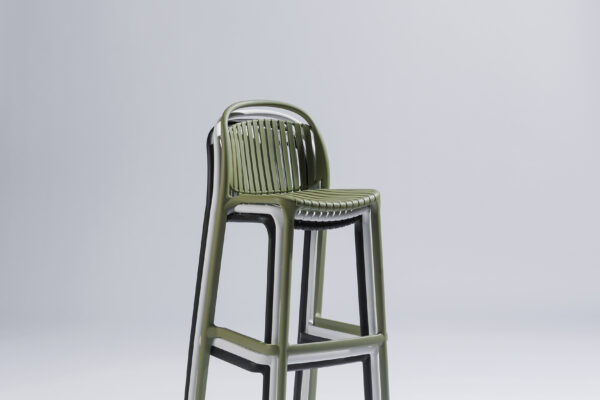 Three Strato bar stools in different colors stacked on top of each other in a stylish photo studio with a neutral background and soft lighting, where the modern design and efficient stackability take center stage.