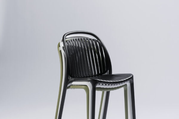 Three Strato chairs in different colors stacked on top of each other in a stylish photo studio with a neutral background and soft lighting, where the modern design and efficient stackability take center stage.