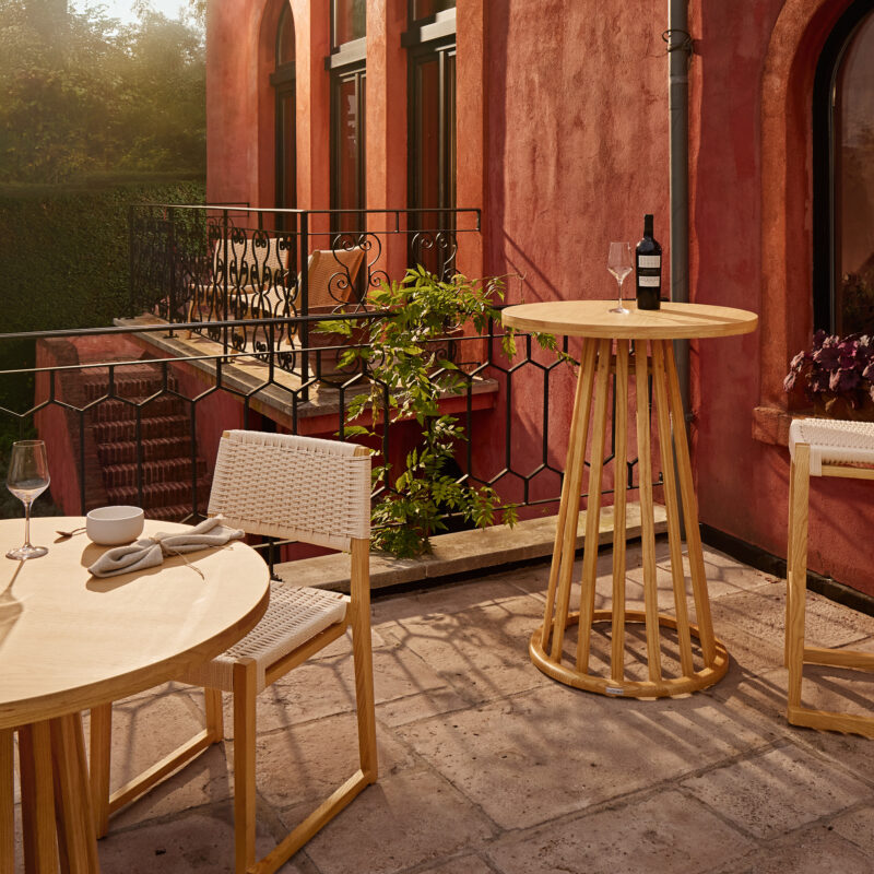 Mundi partytafel en dinertafel met bijpassende stoel en barkruk op een zonnig terras.