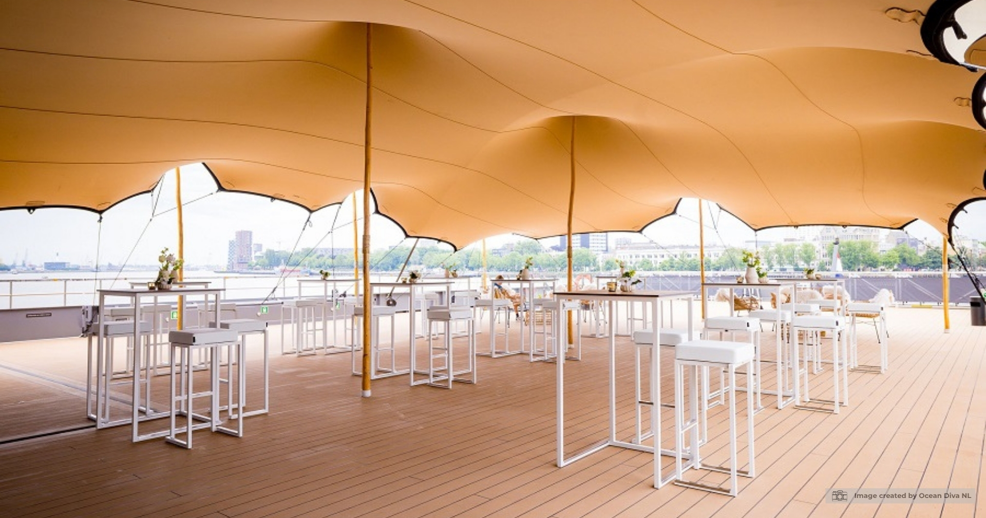 Kubo collectie met witte statafels en barkrukken op een terras eventlocatie onder een stijlvolle stretch tent met uitzicht op het water