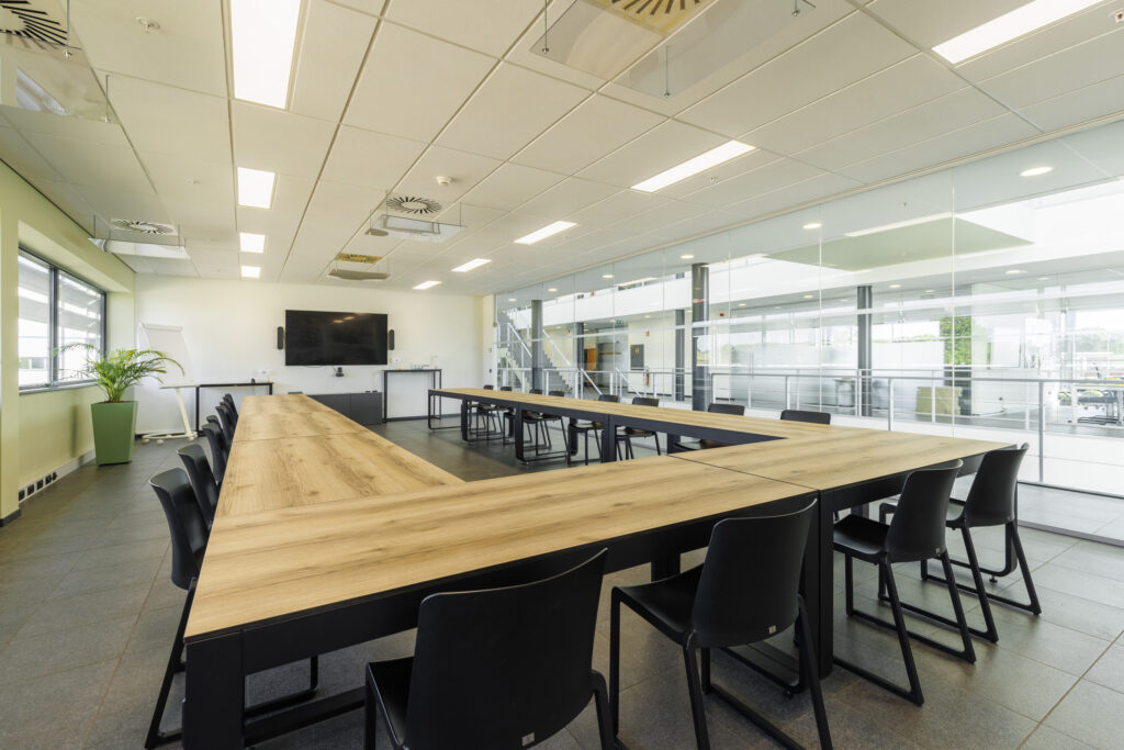 Grote vergaderruimte met Flow tafels en Kasar stoelen in een U-opstelling, gericht naar een scherm en klaar voor een professionele meeting